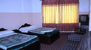 A hotel room with two single beds, a sofa, a television, and a patterned carpet. - Pashupati Plaza (Kathmandu)