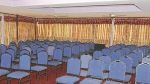 A conference room with rows of blue chairs, a stage, and a ceiling fan. - Pashupati Plaza (Kathmandu)