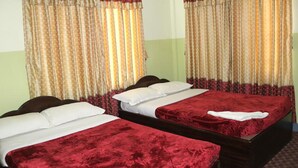 A hotel room with two single beds, each with a red bedspread and white pillows. The room has curtains with a striped pattern. - Pashupati Plaza (Kathmandu)