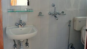 A bathroom with a white sink, glass shelf, and a toilet. - Cherry Garden (Pokhara)