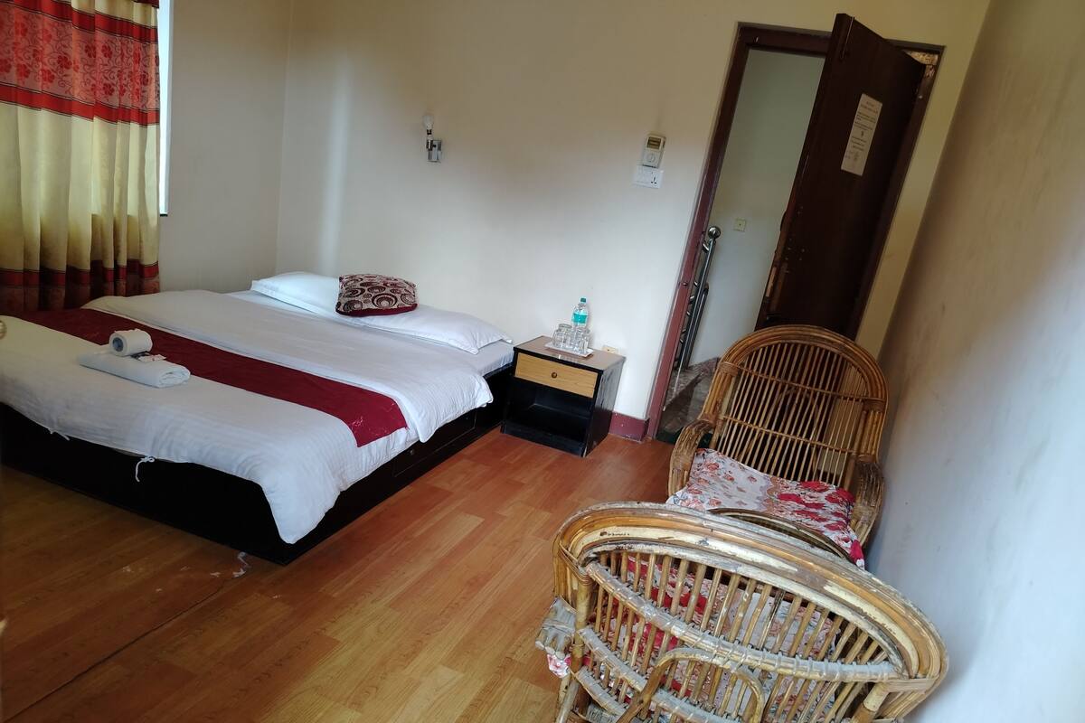 A bedroom with two beds, a nightstand, a chair, and a door.