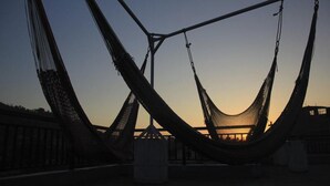 A hammock structure with a metal framework and netting, set against a sunset sky. - Cherry Garden (Pokhara)