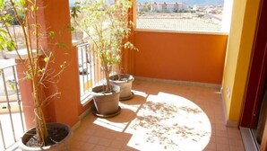 A balcony with potted plants and a view of buildings in the distance. - Park 20 Guesthouse (Olbia)