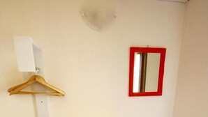 A bathroom with a red flower-shaped chair, a white towel rack, a mirror, and a wall-mounted shelf. - Park 20 Guesthouse (Olbia)