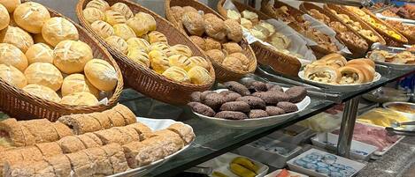 A buffet with various food items including bread, pastries, fruits, and vegetables.