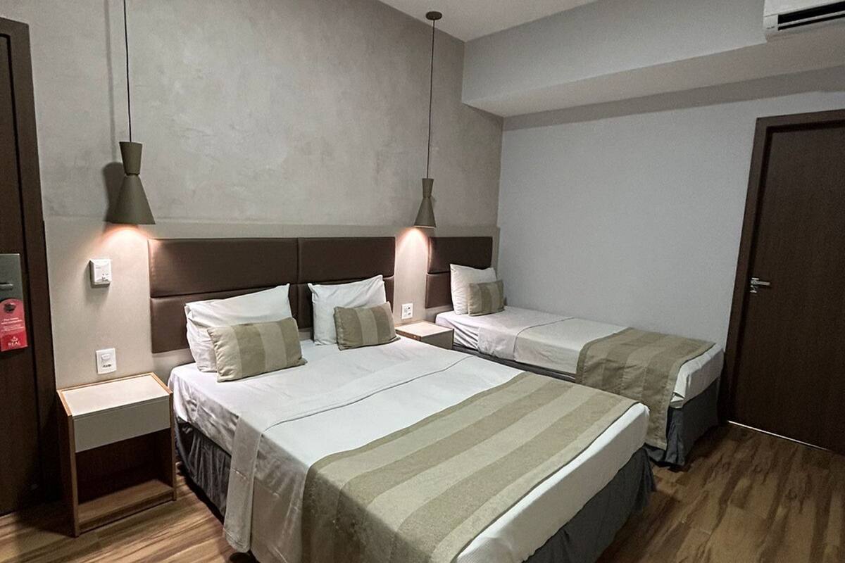 Een hotelkamer met twee bedden, houten vloeren en hanglampen.