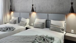 Una habitación de hotel moderna con dos camas, paredes grises e iluminación colgante.