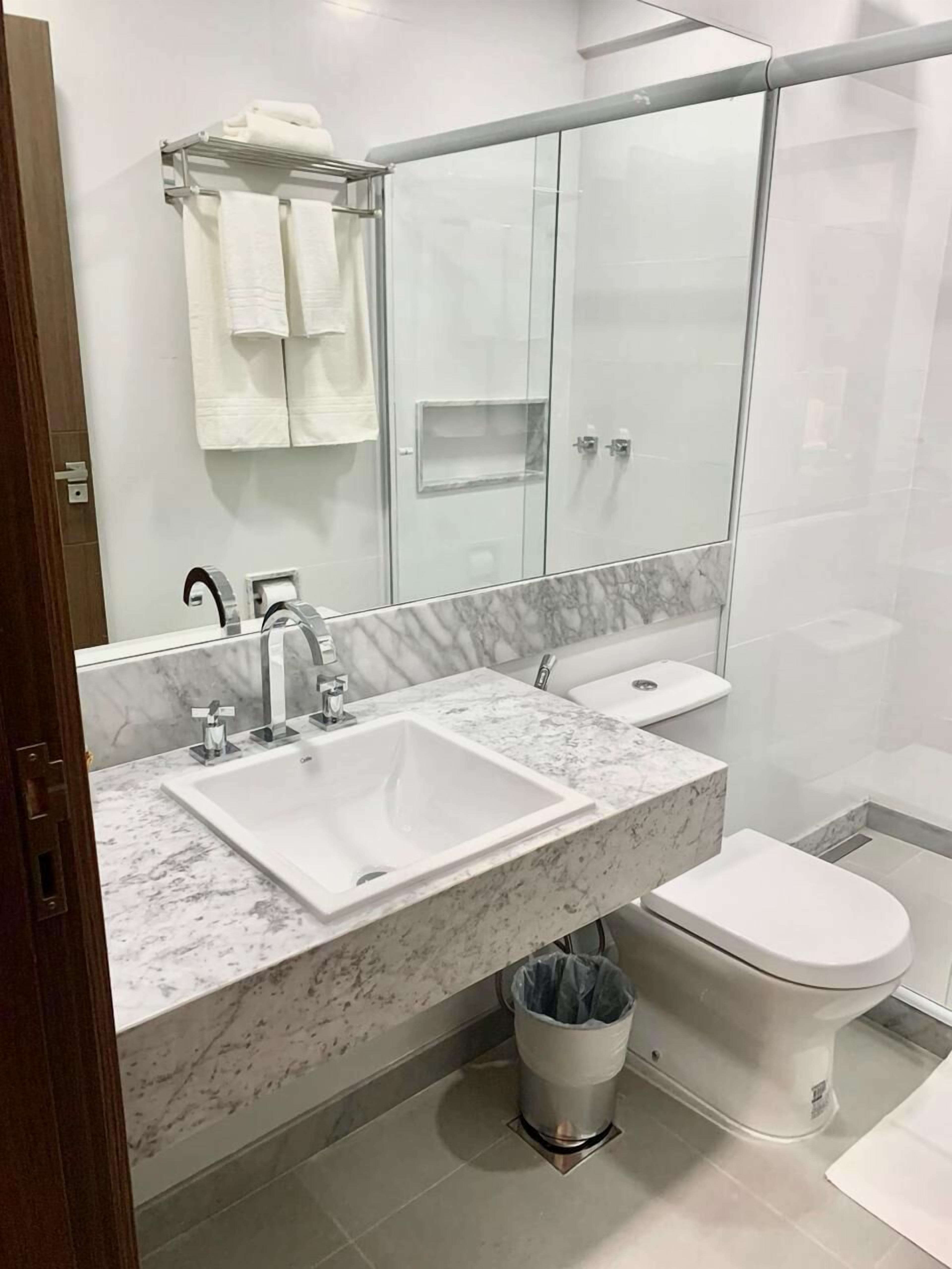 Une salle de bain moderne avec un lavabo en marbre, une douche à parois de verre et des toilettes.