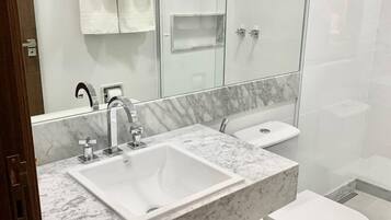 Une salle de bain moderne avec un lavabo en marbre, une douche à parois de verre et des toilettes.