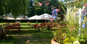 An outdoor seating area with tables and chairs under white tents with logos. - 4 Żywioły Falenty Hotel & Conference Center (Raszyn)