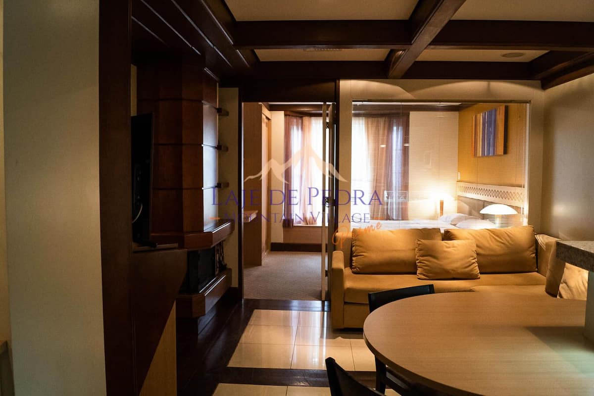 Una sala moderna con un sofá, una mesa de comedor y una cocina visible a través de un umbral abierto.