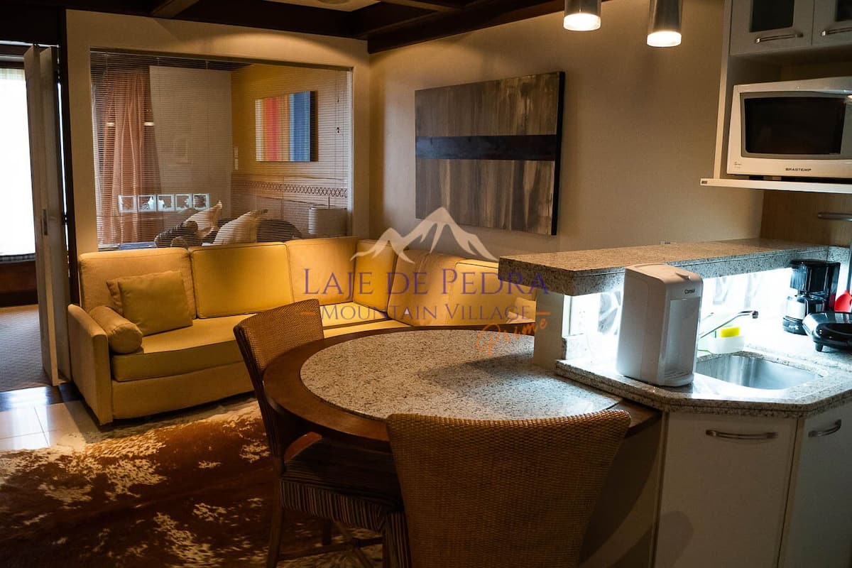 Una sala acogedora con sofá, una mesita redonda y una cocina equipada con microondas y cafetera.