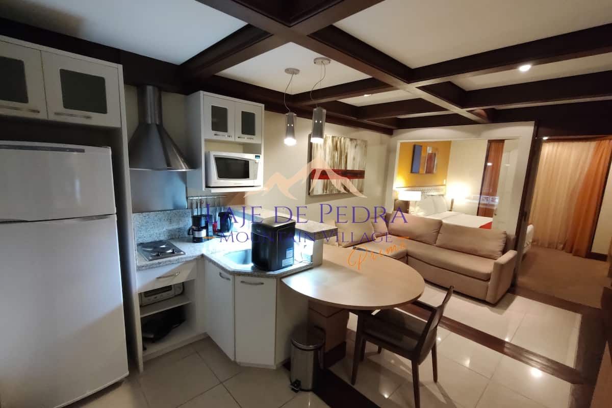 Una cocina moderna con armarios blancos, microondas y cafetera. Hay un comedor con mesa y sillas.