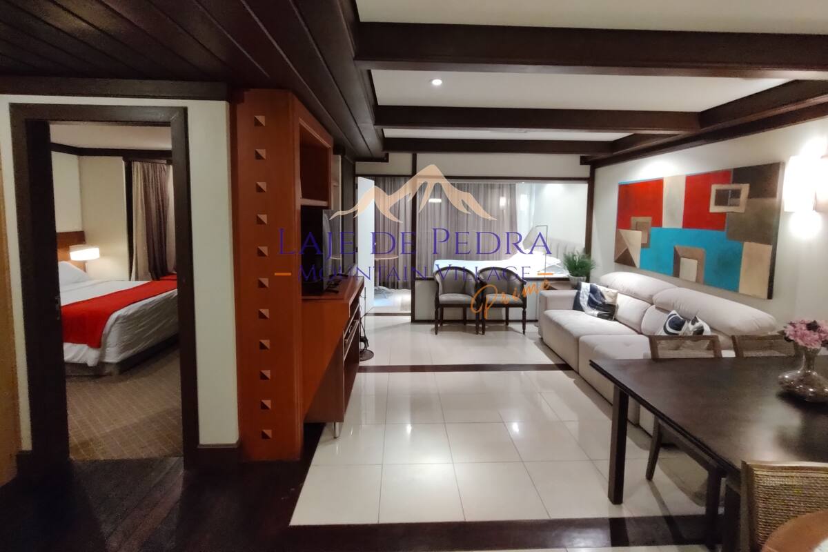 Habitación de hotel con cama, separador de madera, sofá, mesa de comedor y vistas al exterior.