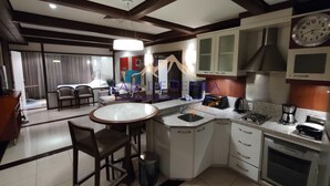 Een moderne keuken met een centraal eiland, witte kasten en een inbouwoven.