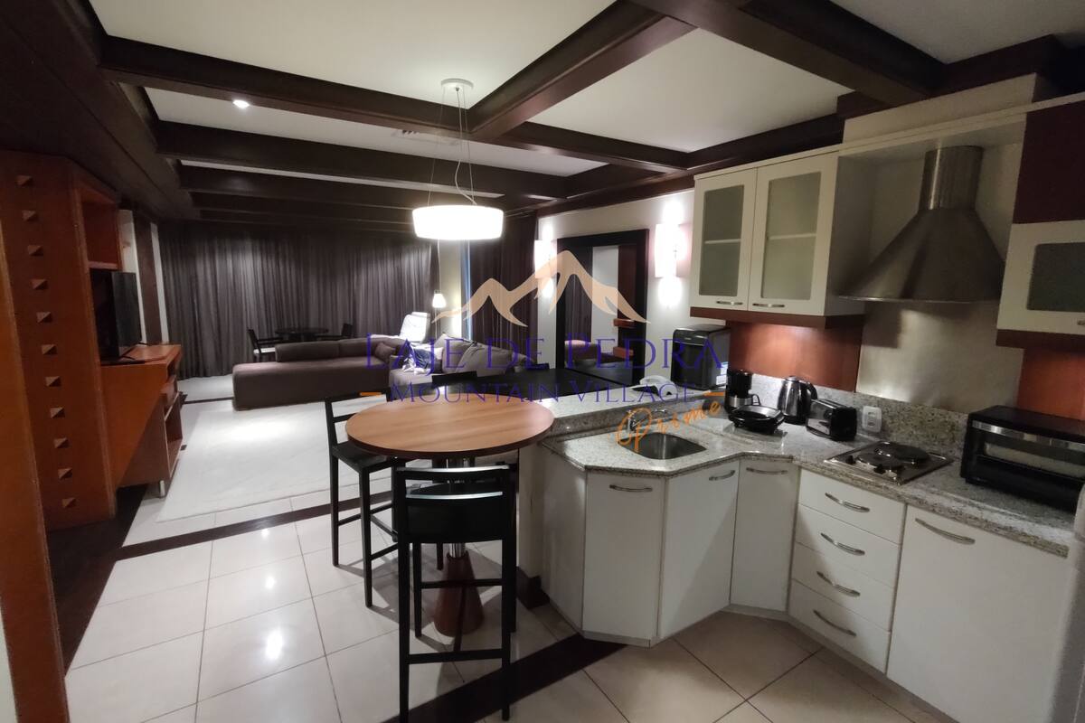 Una cocina moderna con armarios blancos, una mesa de comedor de madera y un horno empotrado.