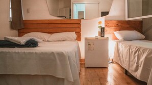 Camera d'albergo con due letti, testiere in legno, un comodino con lampada e uno specchio a parete.