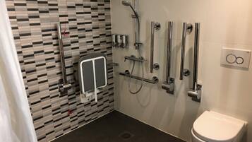 Ein modernes Badezimmer mit Wandfliesen im Schachbrettmuster, einer weißen Toilette und einer Dusche mit mehreren Bedienelementen.