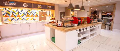 A modern kitchen area with a coffee station, a toaster, and a counter with various food items.