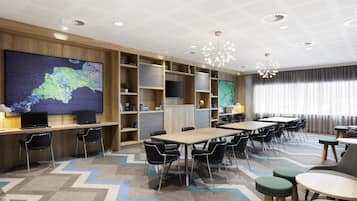A modern conference room with a large flat-screen TV, wooden paneling, and a patterned carpet.