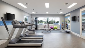 Uma academia com esteiras, bolas de exercício e halteres.
