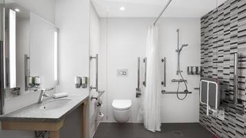 A modern bathroom with a granite sink, a toilet, a shower with a glass door, and a mirror.
