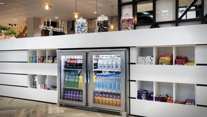 Um interior moderno com uma máquina de vendas automática, prateleiras repletas de lanches e um teto decorativo.