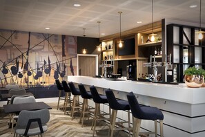 Un bar moderne doté d’un long comptoir, de nombreux tabourets et d’une grande variété de bouteilles et de verres.
