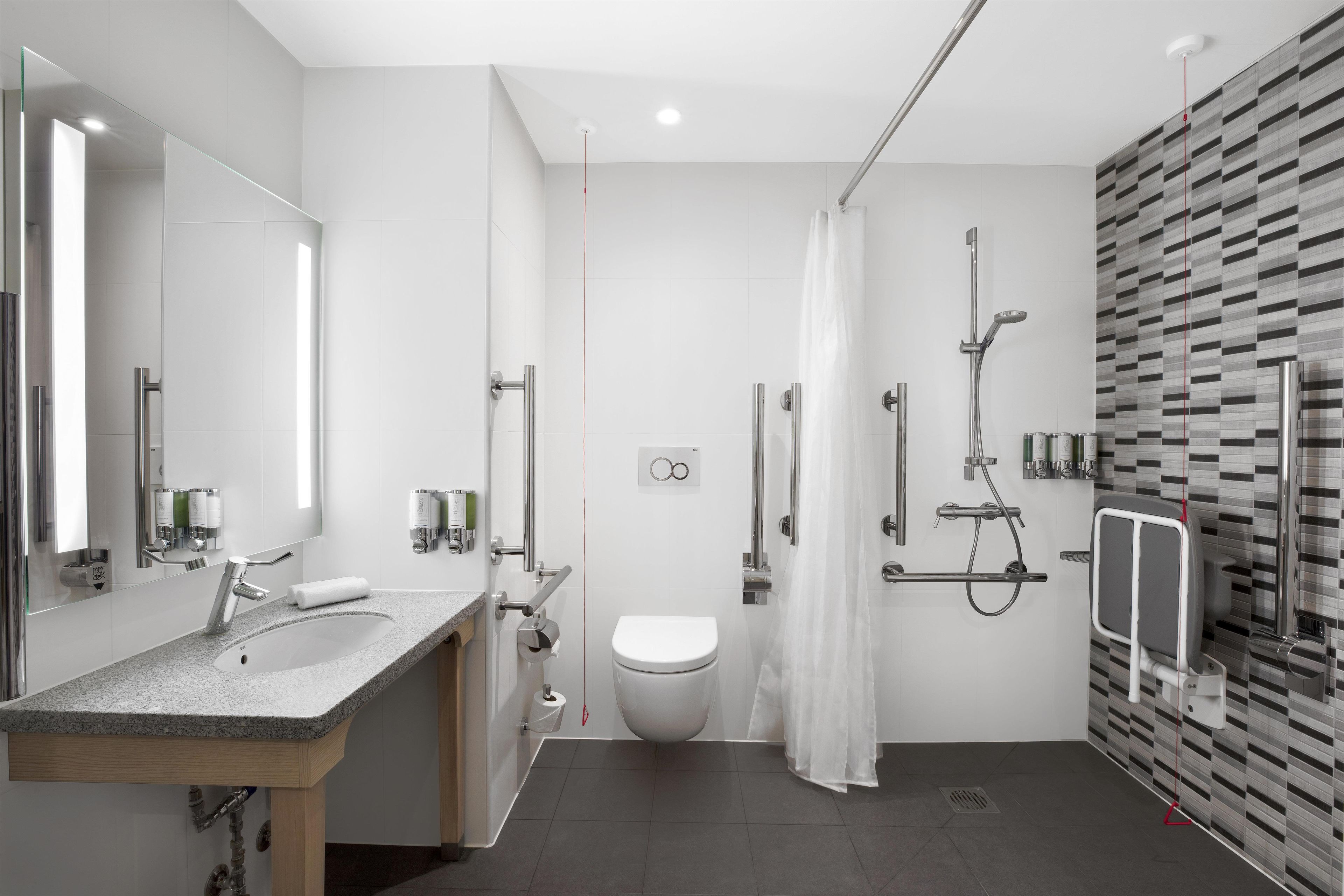 A modern bathroom with a granite countertop sink, a toilet, and a shower area with a glass door.