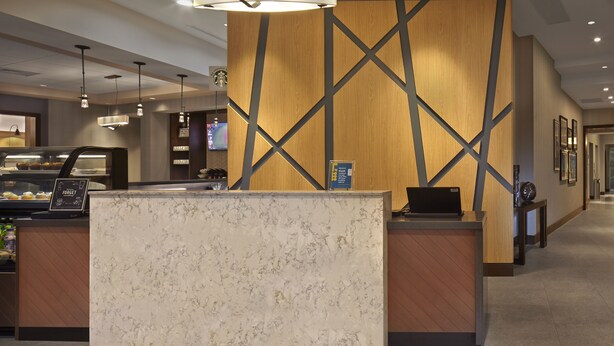 A hotel reception area with a marble counter, wooden accents, and pendant lighting.