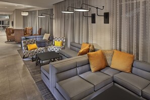 Un área de descanso moderna con un sofá seccional gris, sillones estampados y una mesita.