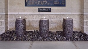 Une cheminée surmontée de trois vases cylindriques et d’une vue de la ville encadrée.