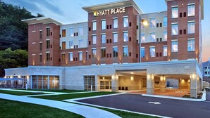A multi-story hotel with a prominent 'Hyatt Place' sign, a covered entrance, and a parking area.