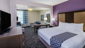 Habitación de hotel con una cama grande, un escritorio, un televisor y una zona de estar con una silla y una mesa.