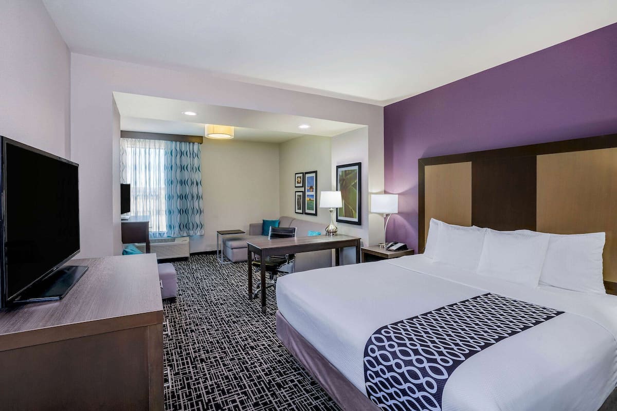 Une chambre d’hôtel avec un grand lit, un bureau, une télévision et un coin salon comprenant une chaise et une table.