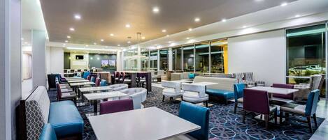 A modern restaurant with multiple seating areas, including booths and tables, and a patterned carpet.