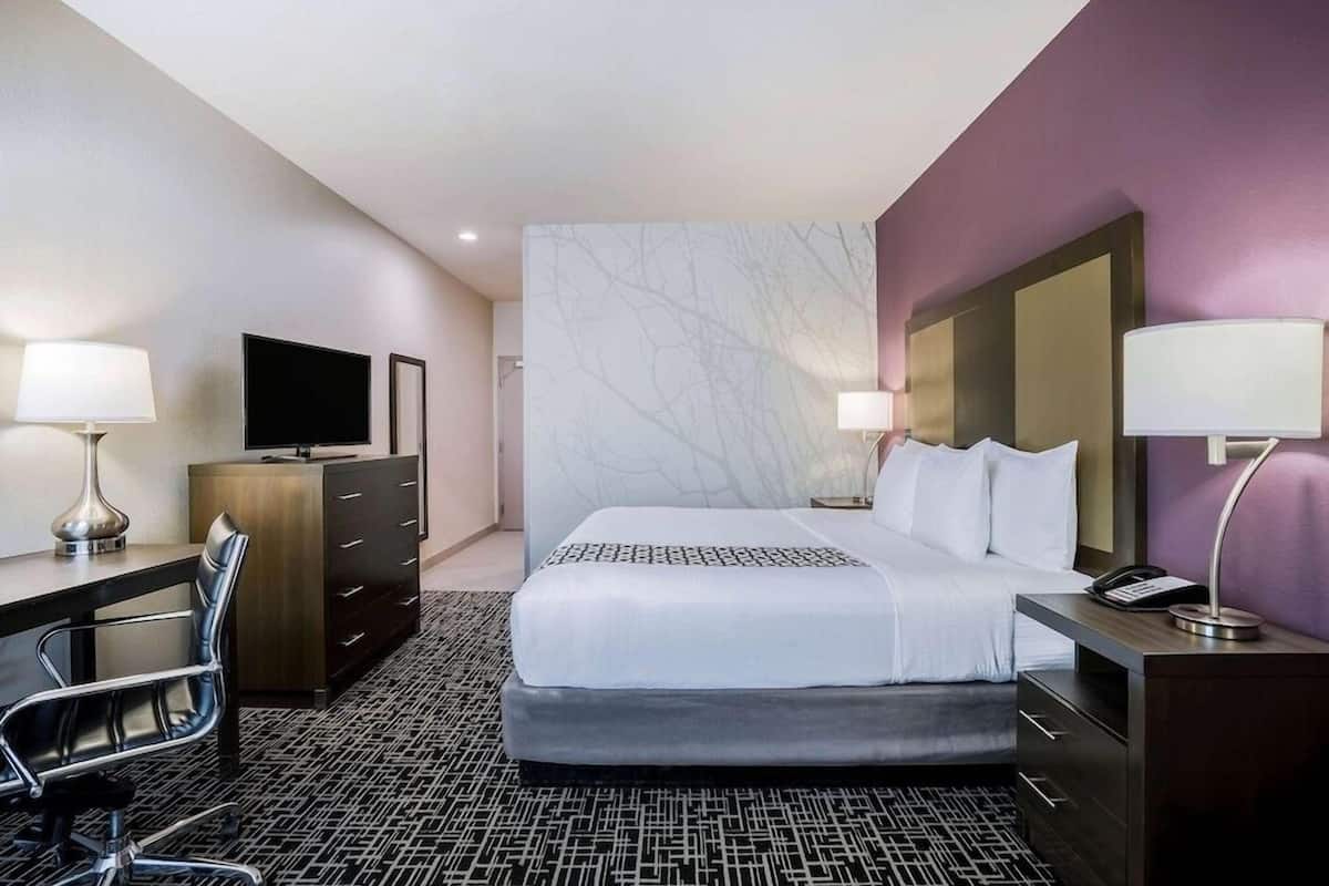 Une chambre d’hôtel équipée d’un lit, d’un bureau, d’une chaise, d’une télévision et de lampes.