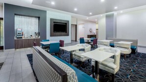 Un moderno vestíbulo de hotel con áreas de estar, un televisor y una recepción con servicios.