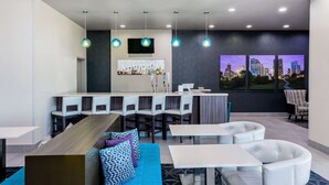 Un moderno vestíbulo de hotel con zona de bar, asientos y vistas a la ciudad.
