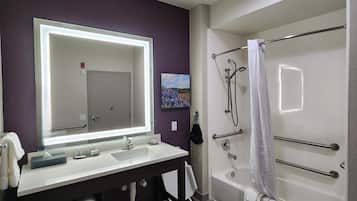 Un baño moderno con un espejo grande, lavamanos blanco y bañera.