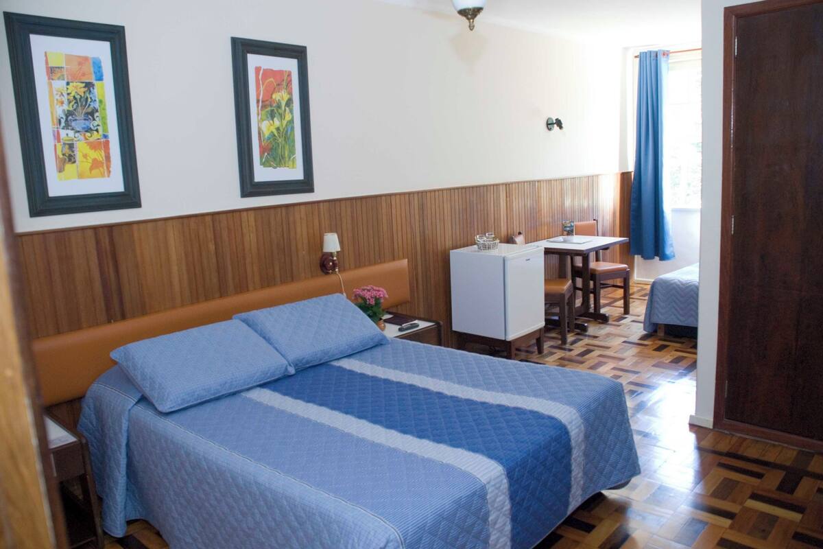 A bedroom with a bed, a desk, and a chair.