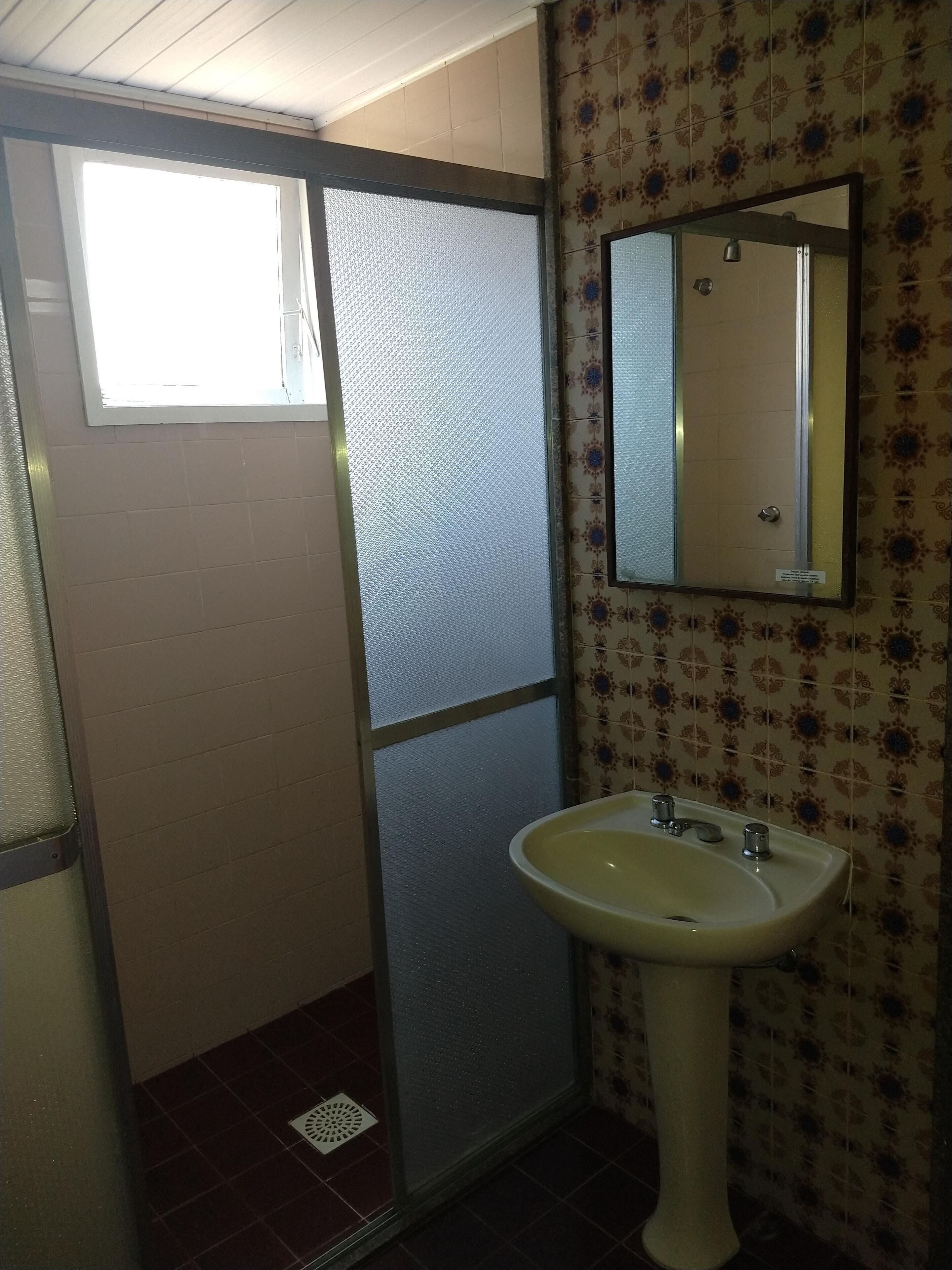 A bathroom with a window, a sink, and patterned tiles.