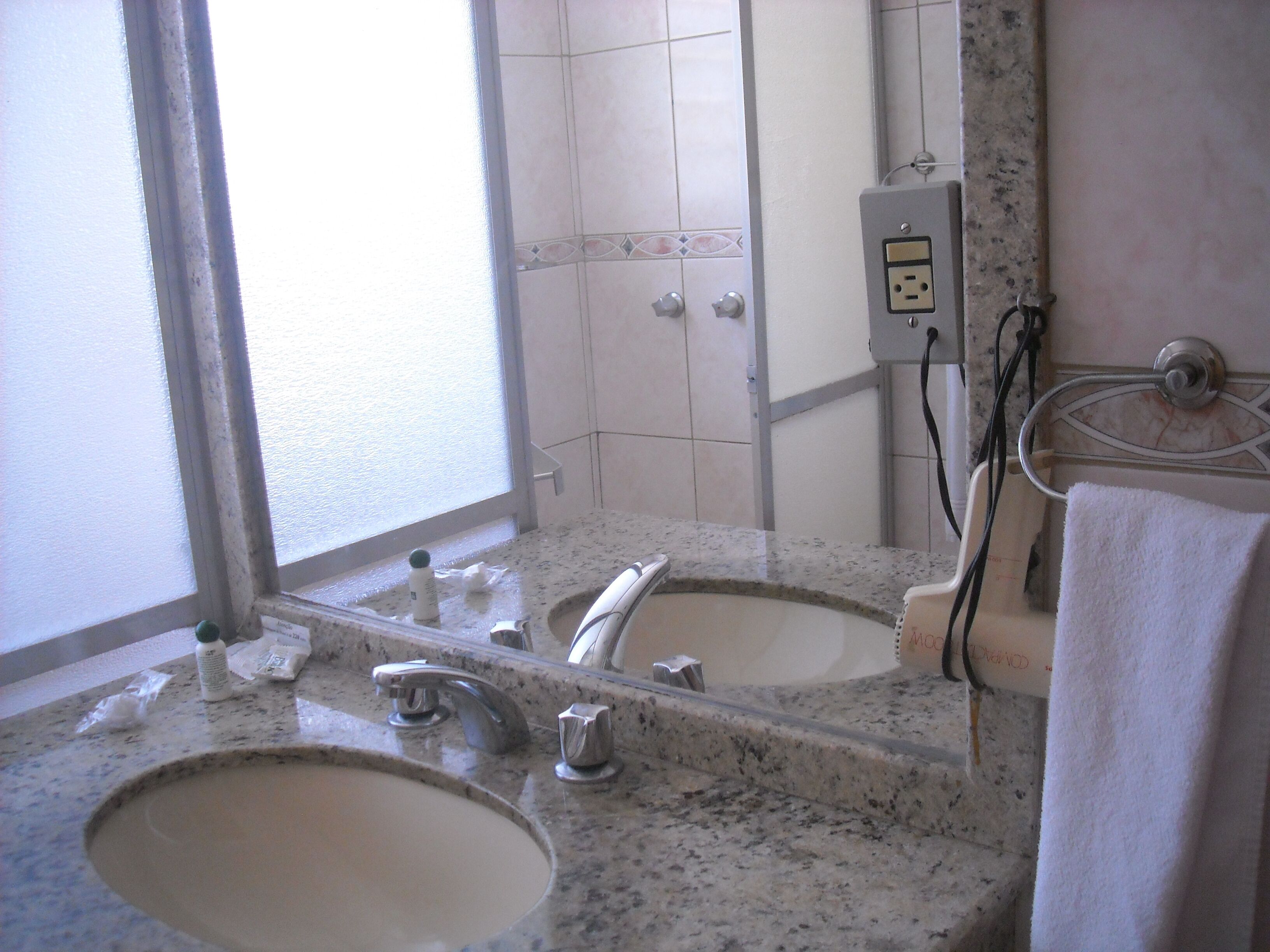 Un baño con lavamanos, espejo y toallero.