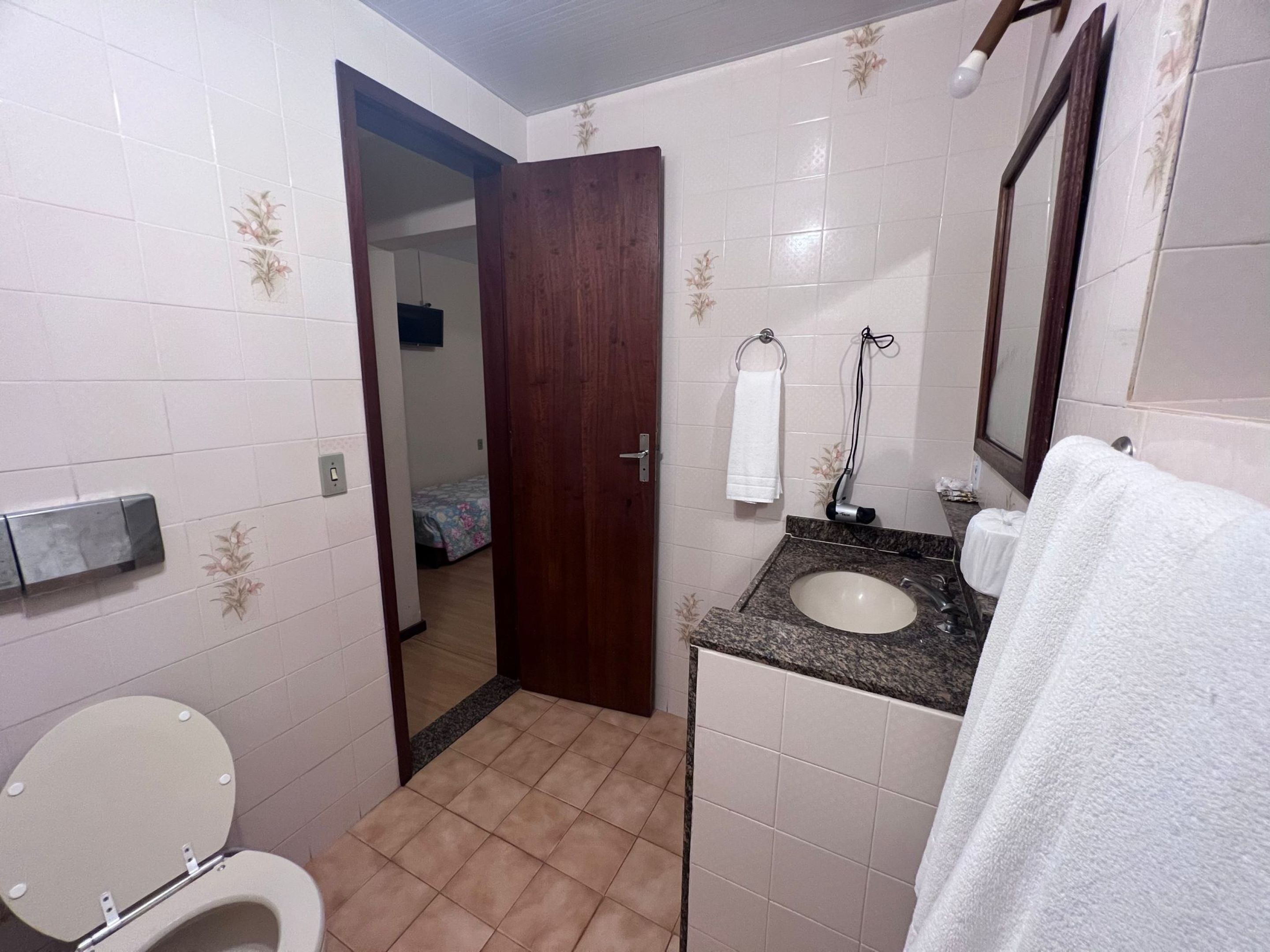A small bathroom with a toilet, sink, and a mirror.