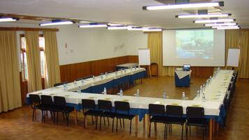 A conference room with a long table, chairs, a projector screen, and a podium.