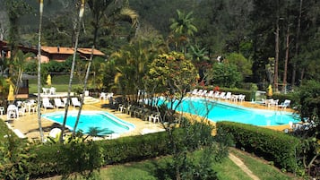 Una piscina al aire libre, sombrillas, sillones reclinables de piscina