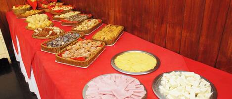A buffet table with various food items including pastries, meats, and cheeses.