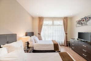 Habitació d'hotel amb dos llits, televisió, un aparador i una finestra amb cortines.