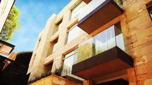 Un edificio moderno con fachada de piedra, ventanas amplias y un balcón.