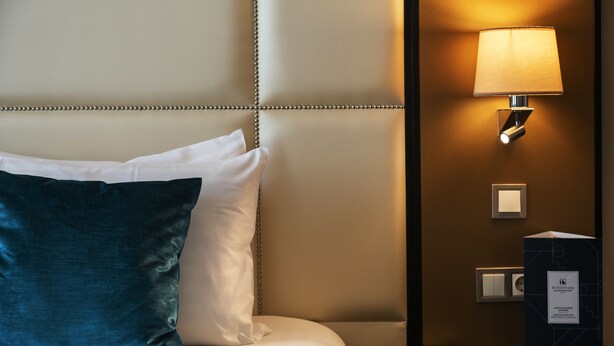 A hotel room with a bed, a nightstand, a lamp, and a wall-mounted light switch. - Eurostars Danube Budapest (Budapest)